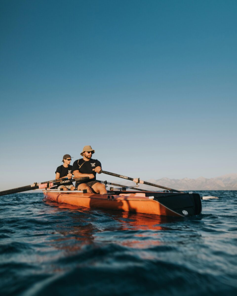 Two men rowing on a calm lake during the day in Antalya, Türkiye, showcasing teamwork and sport.